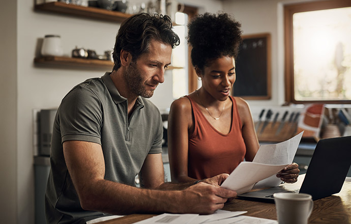 A couple sitting at their dining table reviewing important documents.